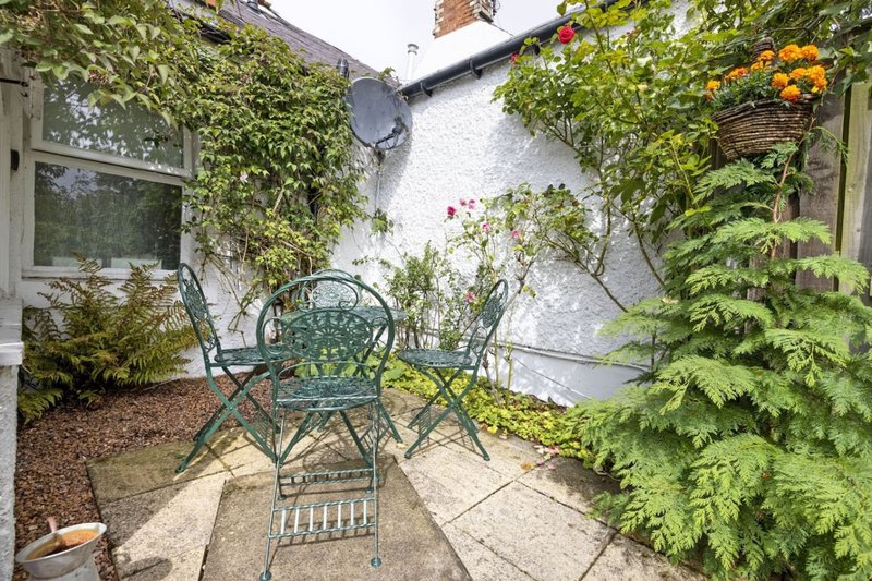 Sheltered courtyard patio with metal garden chairs, ivy-covered walls, and potted plants