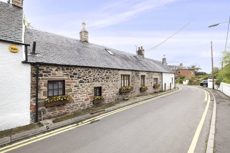 Stone cottage on quiet village street with slate roof and front garden planters