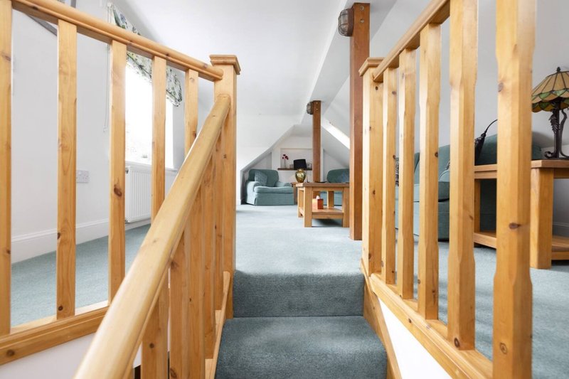 Open-plan loft space with wooden beams, exposed rafters, and carpeted flooring throughout