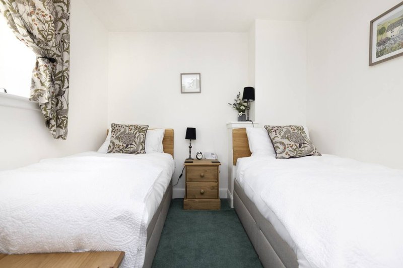 Twin bedroom with two single beds, wooden bedside table, patterned cushions and curtains