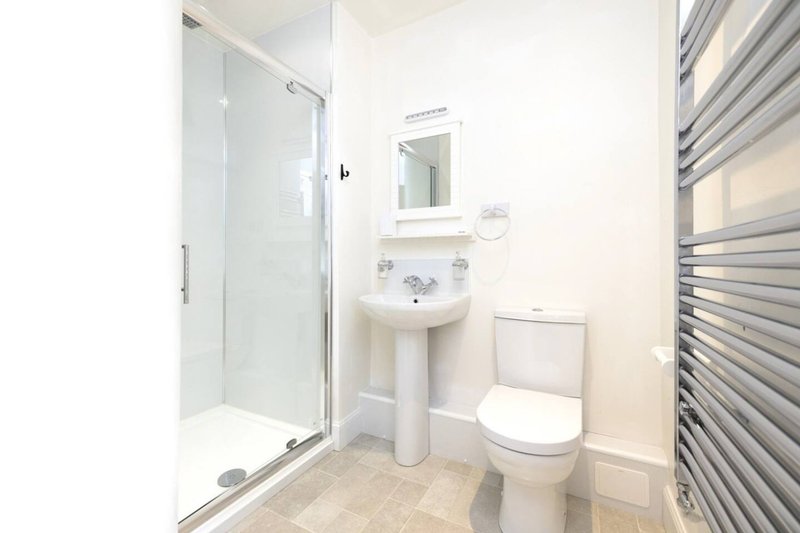 Modern bathroom with shower enclosure, pedestal sink, toilet and heated towel rail
