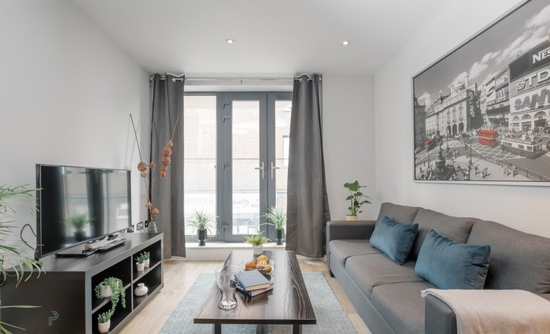 Modern living room with grey sofa, TV, coffee table and large window with grey curtains