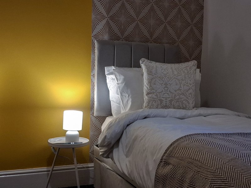 Modern bedroom with double bed, patterned headboard, decorative pillows and bedside lamp