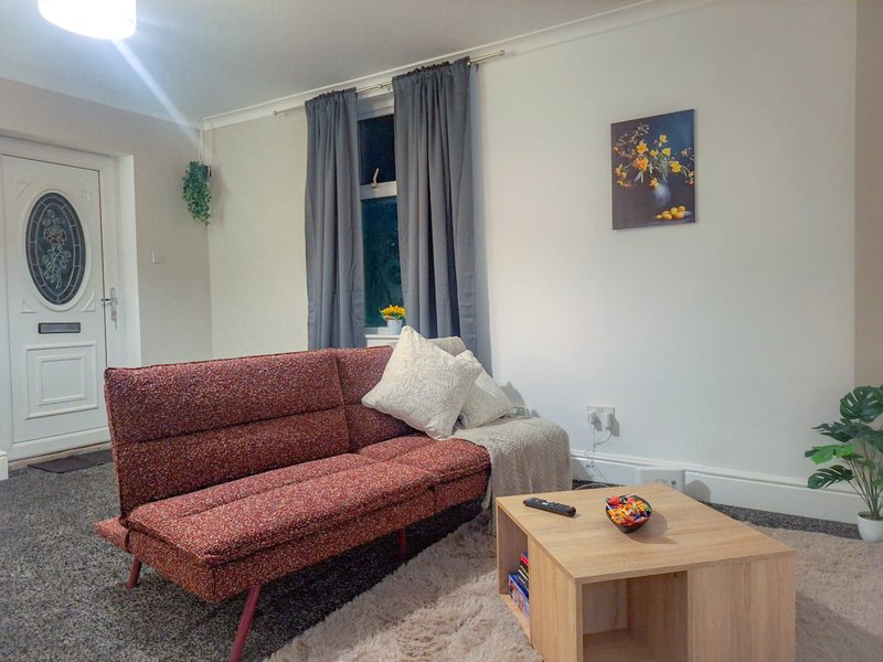 Living room with red sofa, wooden coffee table, window with grey curtains, and wall art