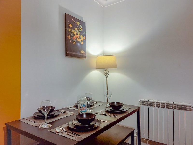 Dining table set for two with lamp, artwork, and radiator visible
