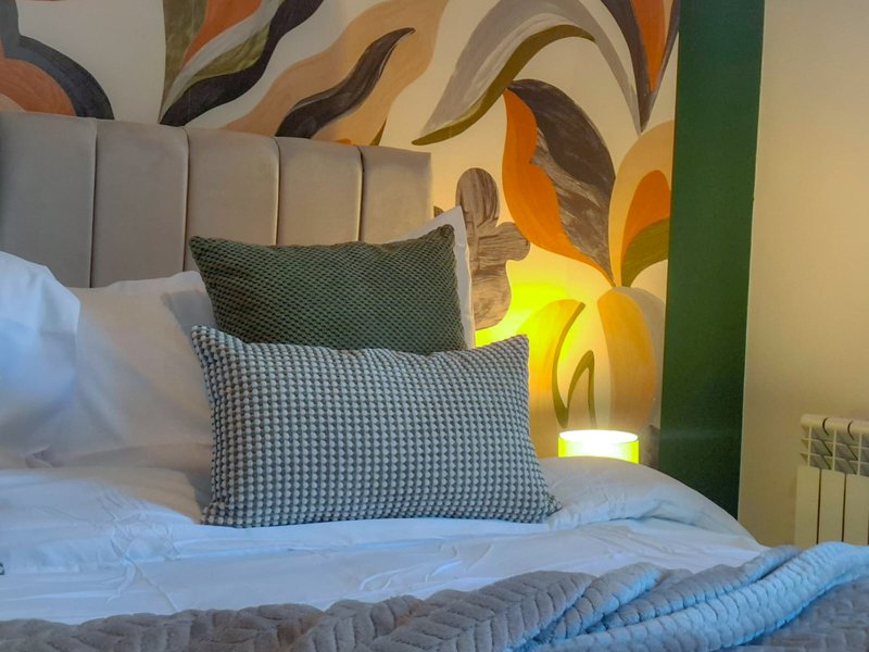 Modern bedroom with patterned headboard, decorative pillows, colorful abstract wall art