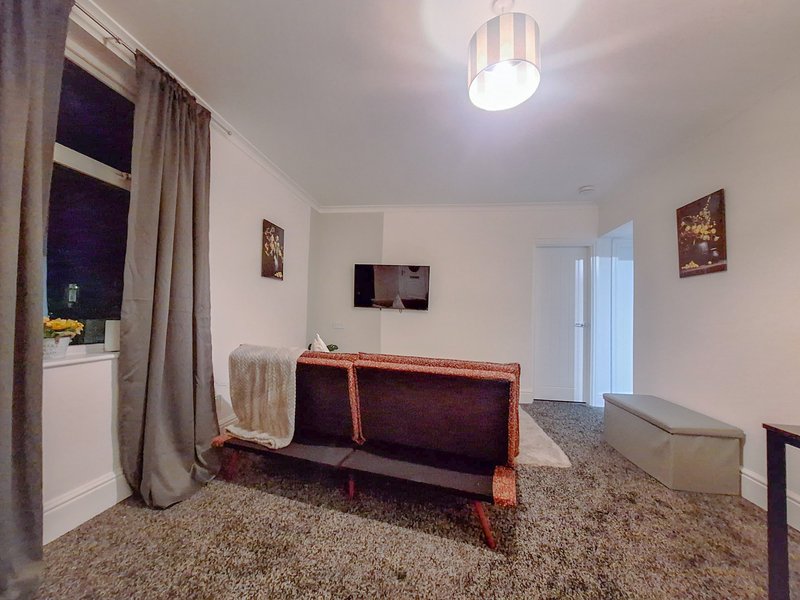 Living room with burgundy sofa, window with curtains, ceiling light, and wall art