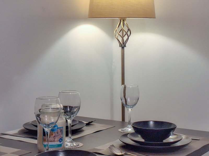 Dining table set with place settings, glassware, water bottle and floor lamp