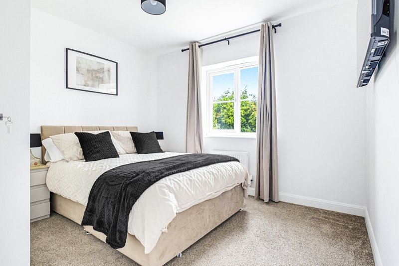 Bright bedroom with double bed, black and cream bedding, framed wall art, and garden view through window