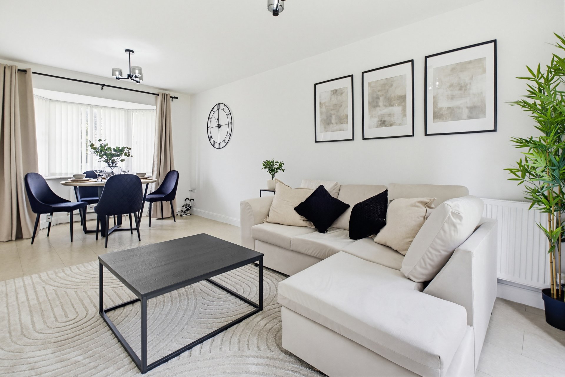 Bright living room with cream sofa, black coffee table, dining area and wall art