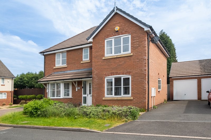 Red brick two-story house with driveway, garage, and front garden