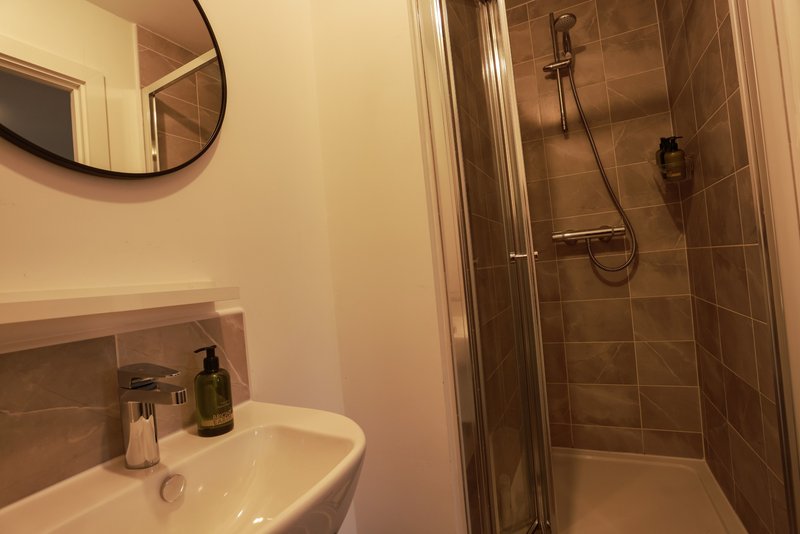 Modern bathroom with sink, mirror, shower enclosure and brown tile walls