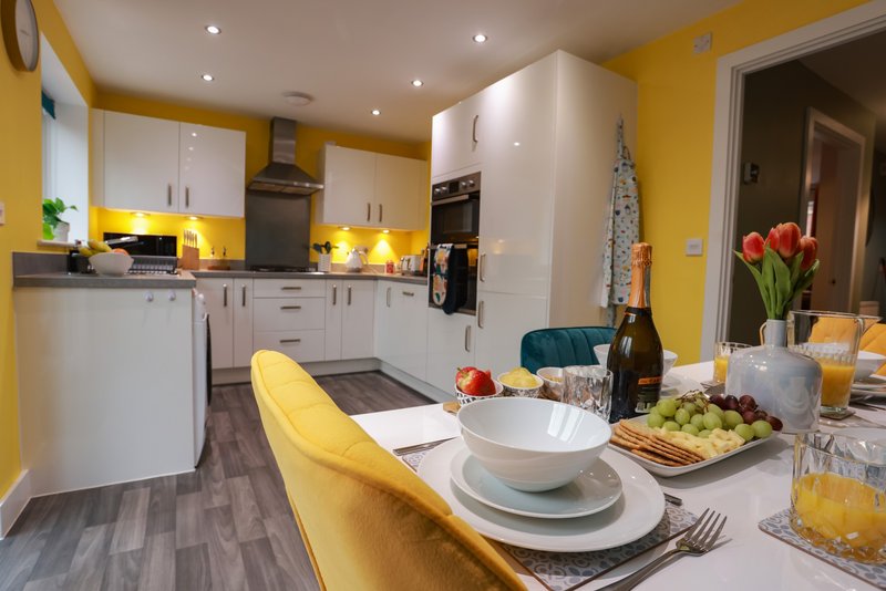Modern kitchen-diner with yellow walls, white cabinetry, dining table set for a meal