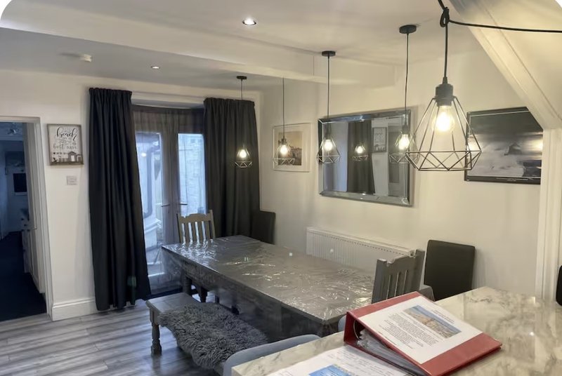 Modern dining room with marble table, pendant lighting, dark curtains and framed wall art