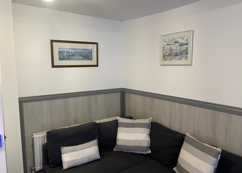 Corner seating nook with black upholstered bench, striped wall paneling, and framed prints