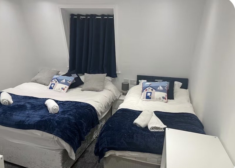 Twin bedroom with two beds, navy bedding, white pillows and dark curtains