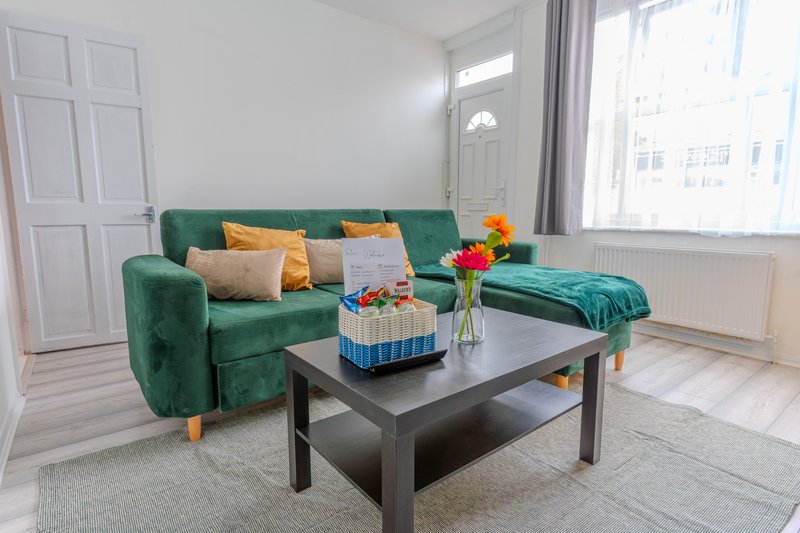 Bright living room with green sofa, black coffee table, yellow accents and large windows