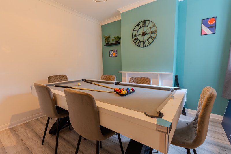 Recreation room with pool table, four chairs, wall clock and colorful wall art