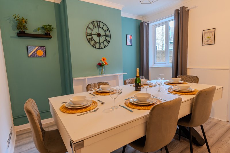 Dining room with set table, upholstered chairs, colorful walls and large clock