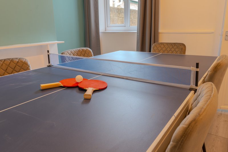 Games room with ping pong table, paddles, net and upholstered chairs
