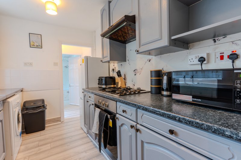 Modern kitchen with white cabinetry, gas range, microwave and granite countertops