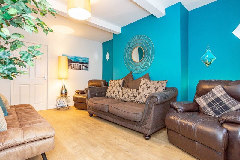 Living room with brown leather sofas, turquoise accent wall, wooden floor and decorative accessories