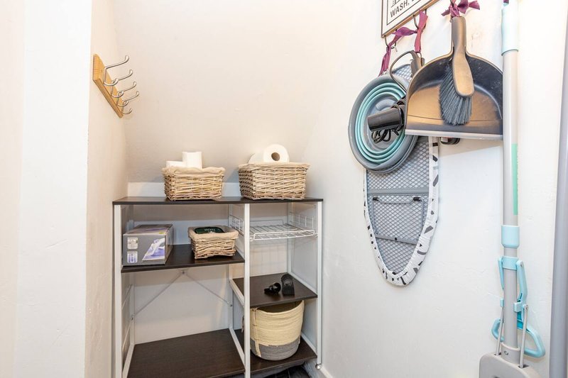 Utility closet with metal shelving unit, woven baskets, storage containers and wall-mounted cleaning supplies