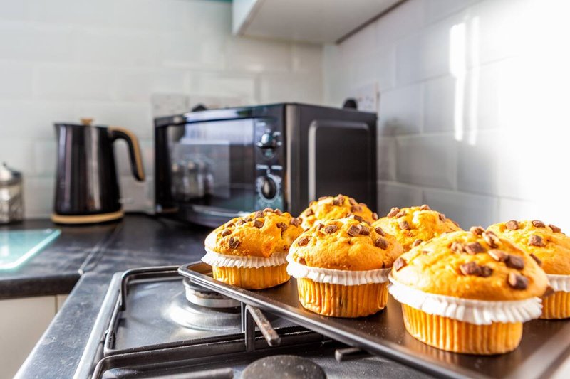 Kitchen counter with freshly baked muffins, utensils, and appliances in background