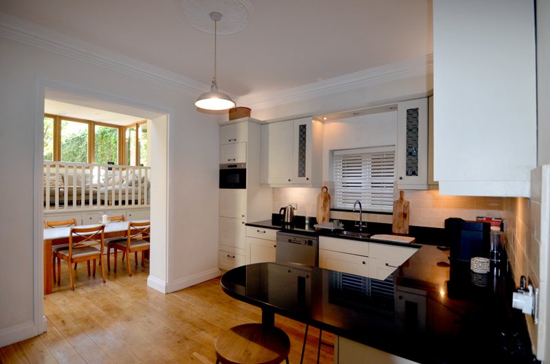 Open-plan kitchen and dining area with black countertop, wooden flooring, and dining table visible through doorway