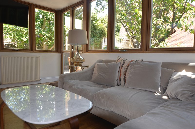 Bright living room with grey sofa, white coffee table, and large windows overlooking garden