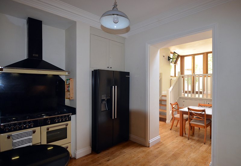 Modern kitchen with cream and black range cooker, black fridge, pendant light, and view through doorway to dining area