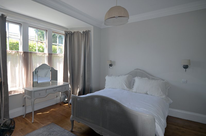 Bright bedroom with double bed, dressing table, pendant light and large window