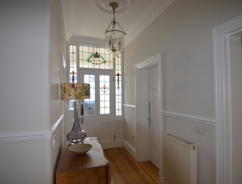 Bright hallway with wooden console table, pendant lights, and doors leading to rooms