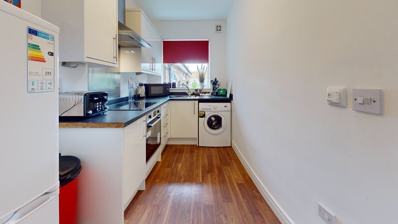 Modern kitchen with cream cabinetry, black countertops, integrated appliances and wooden flooring