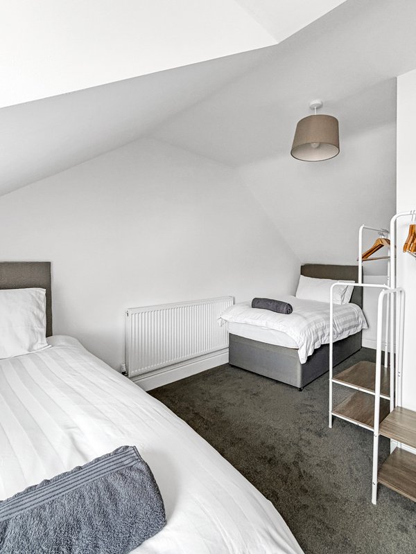 Attic bedroom with sloped ceiling, two single beds, radiator and pendant light