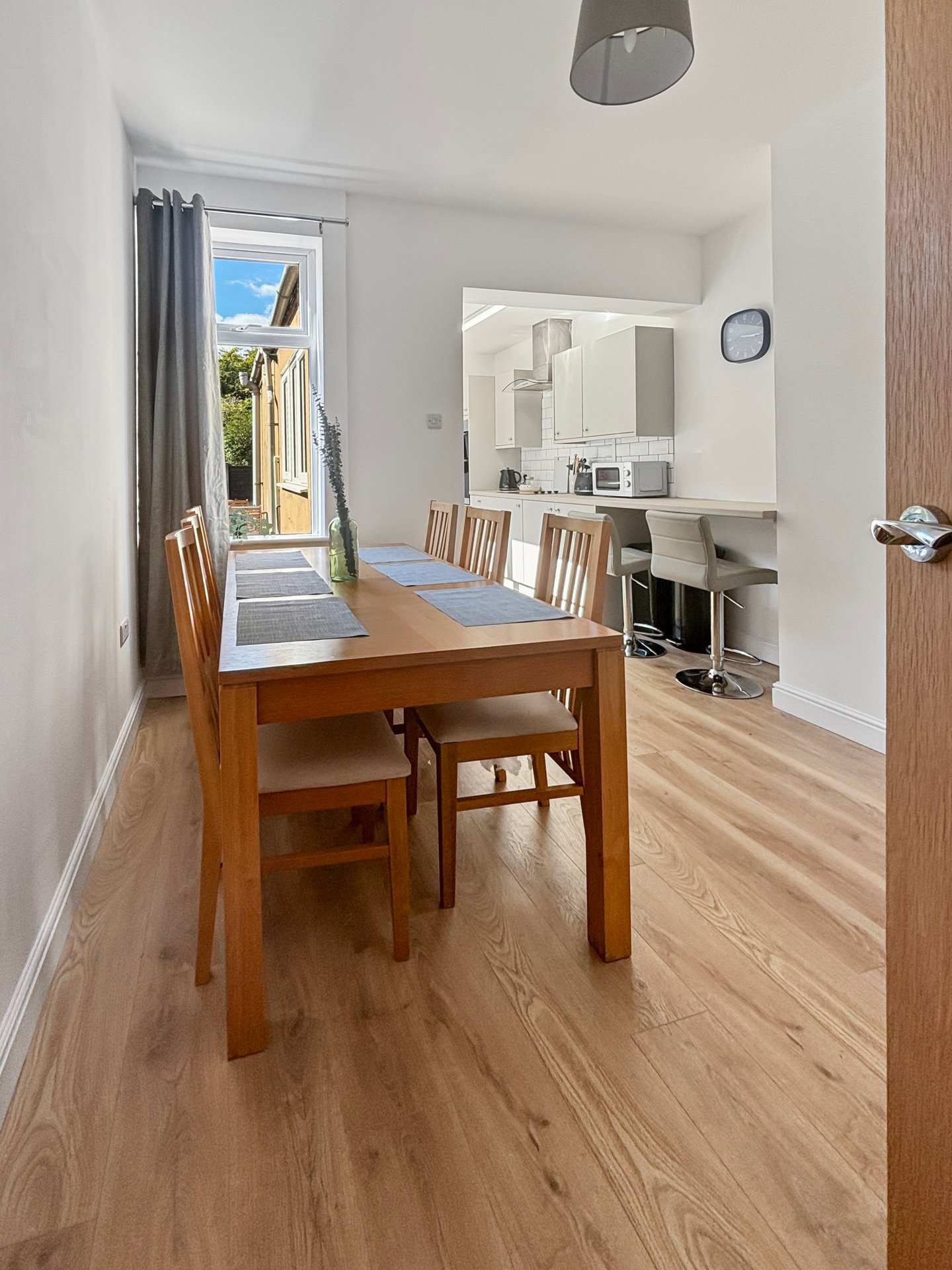 Dining room with wooden table, chairs, and mirror, opening to garden via glass door