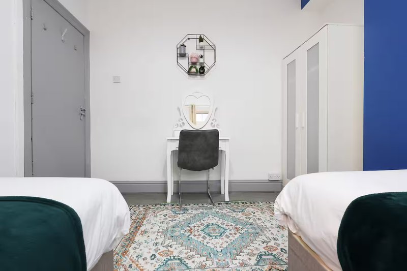 Shared bedroom with two single beds, desk, chair, and decorative wall art