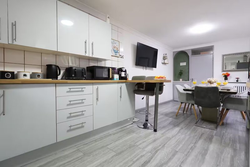 Modern open-plan kitchen and dining area with white cabinetry, black appliances, and wooden dining table