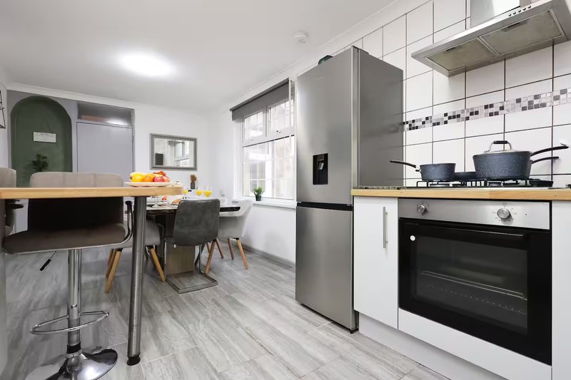 Modern kitchen with stainless steel appliances, white cabinetry, wooden countertops and dining area