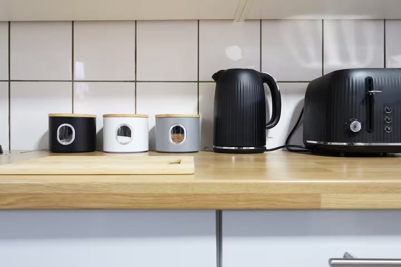 Modern kitchen counter with black kettle, toaster, and decorative storage boxes