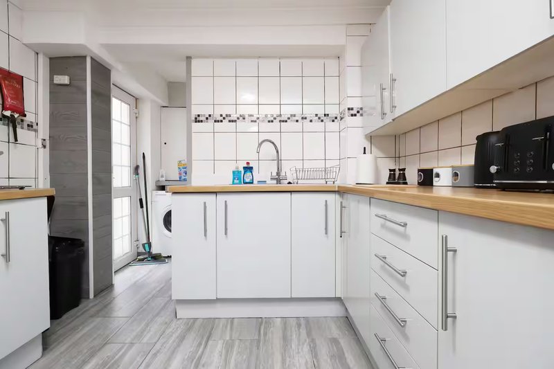 Modern kitchen with white cabinetry, wooden countertops, stainless steel sink and appliances