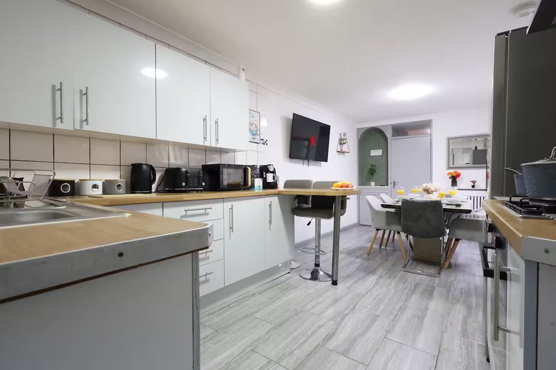 Modern kitchen with white cabinets, wooden countertops, appliances and dining area