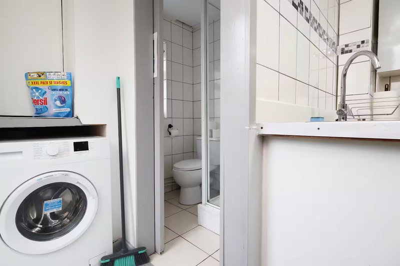 Laundry room with washing machine, cleaning supplies, and access to bathroom