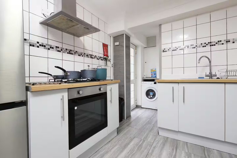 Modern kitchen with white cabinets, wooden worktops, gas hob, built-in oven and washing machine