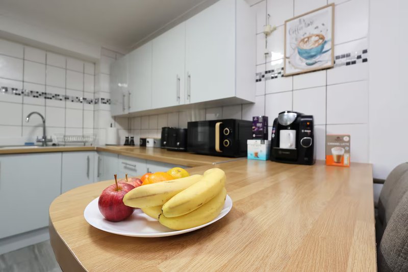 Modern kitchen with white cabinetry, wooden counter, fresh fruit, and small appliances