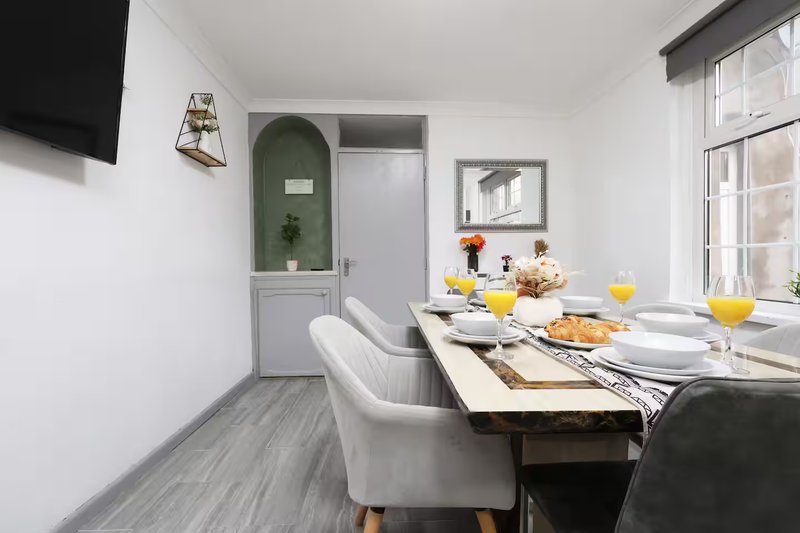 Modern dining area with wooden table, white chairs, yellow flowers and wall art