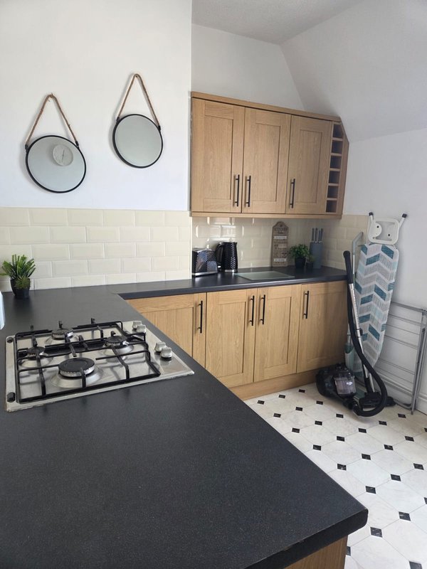 Modern kitchen with wooden cabinets, black countertops, gas hob and circular mirrors