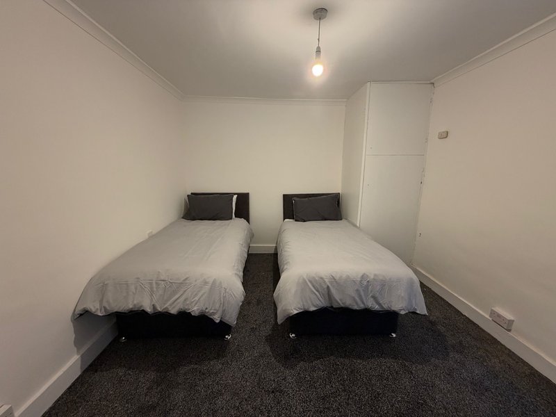 Twin bedroom with two single beds, dark carpet, pendant light, and white walls
