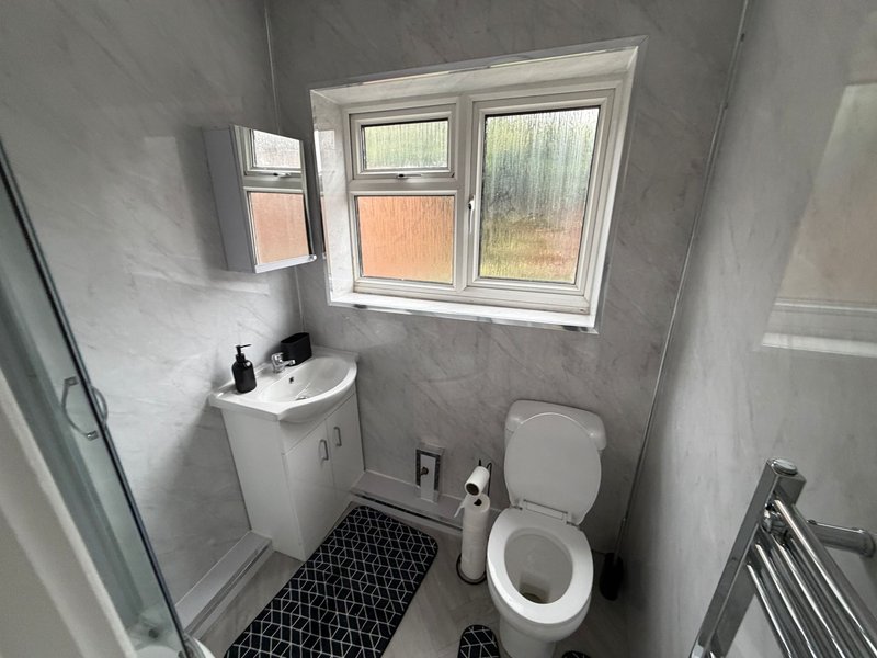 Small bathroom with white toilet, sink, window and black tile flooring