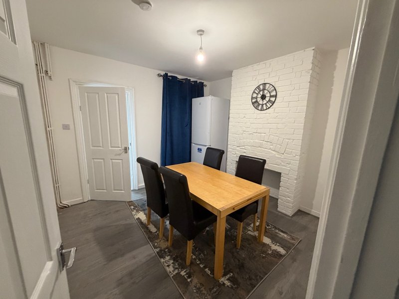 Dining room with wooden table, black chairs, brick accent wall and wall clock